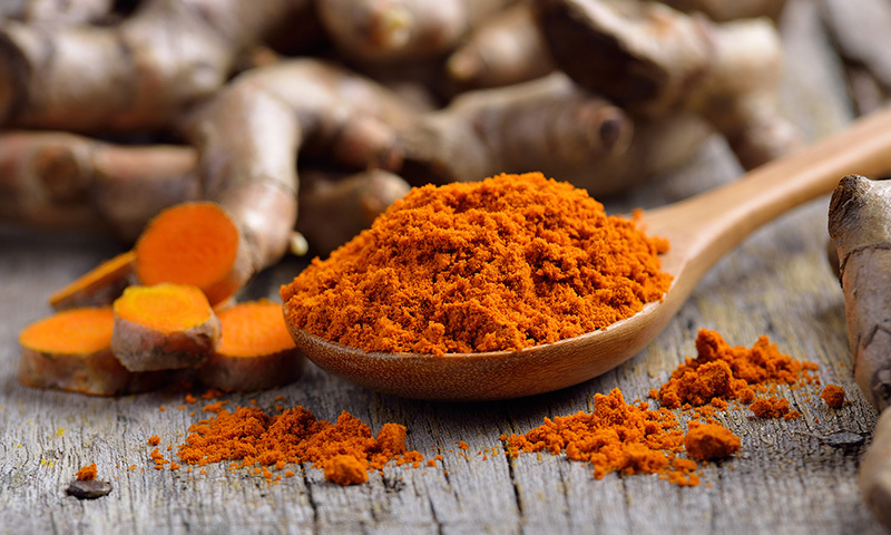 pile of fresh turmeric roots on wooden table