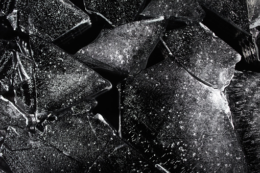 Photo texture of a black and white ice laying on dark background.